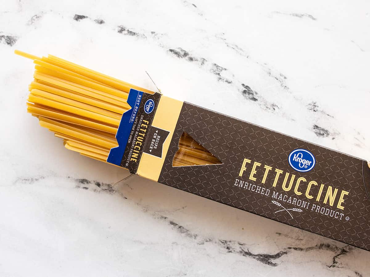 A box of fettuccine open on one end with pasta coming out