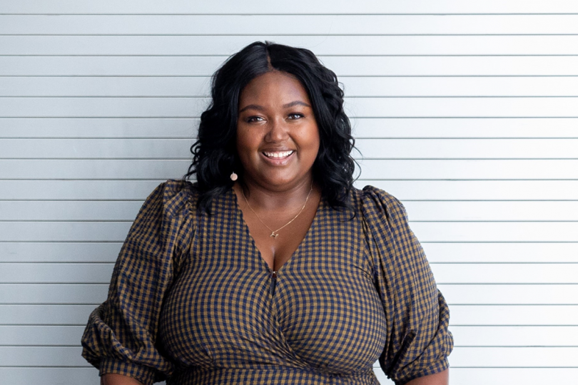 portrait of dark-skinned woman with black shoulder length hair wearing a dark brown and white polka dot blouse