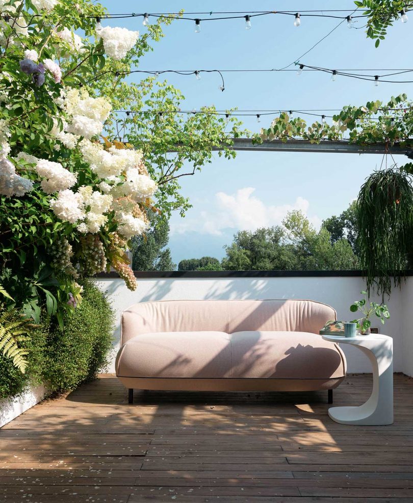 outdoor sofa on patio with side table and greenery