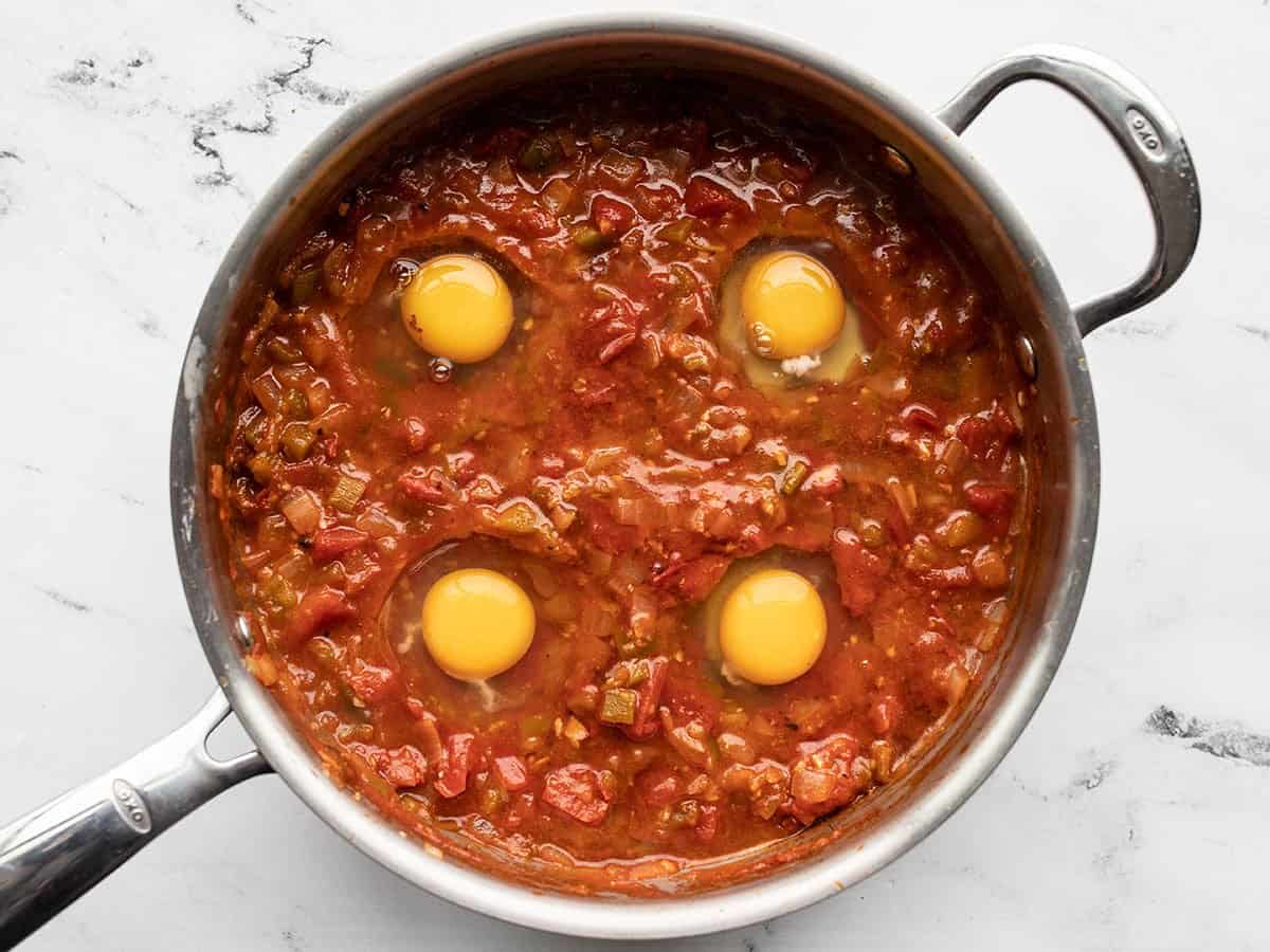 Eggs cracked into the tomato sauce.