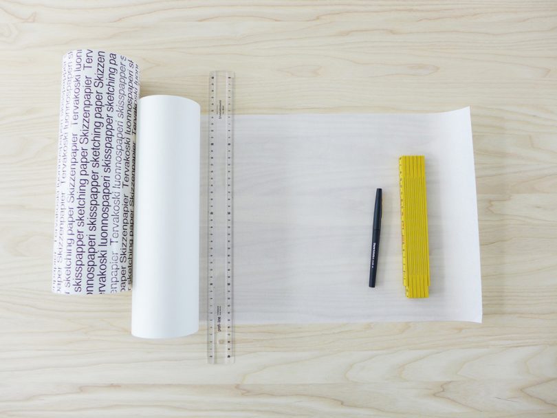 overhead view of light wood table with paper and rulers