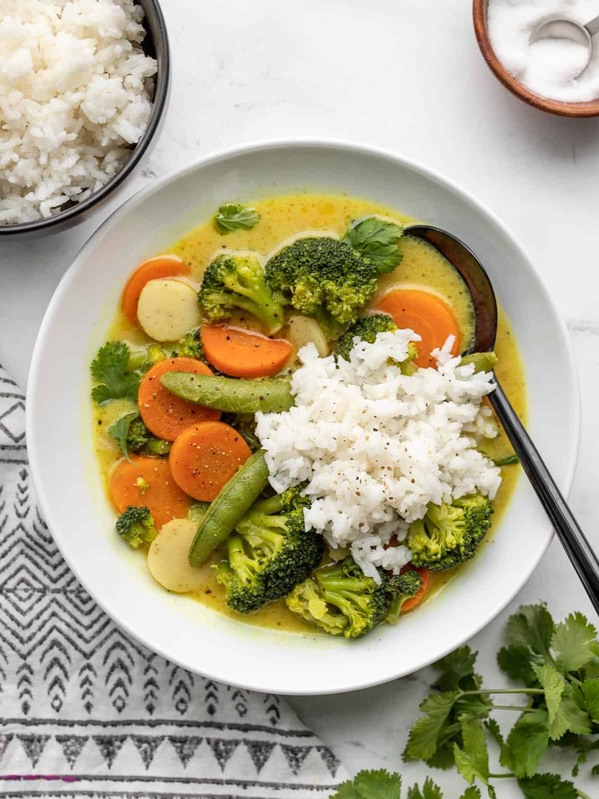 A bowl of curry vegetables with rice on top