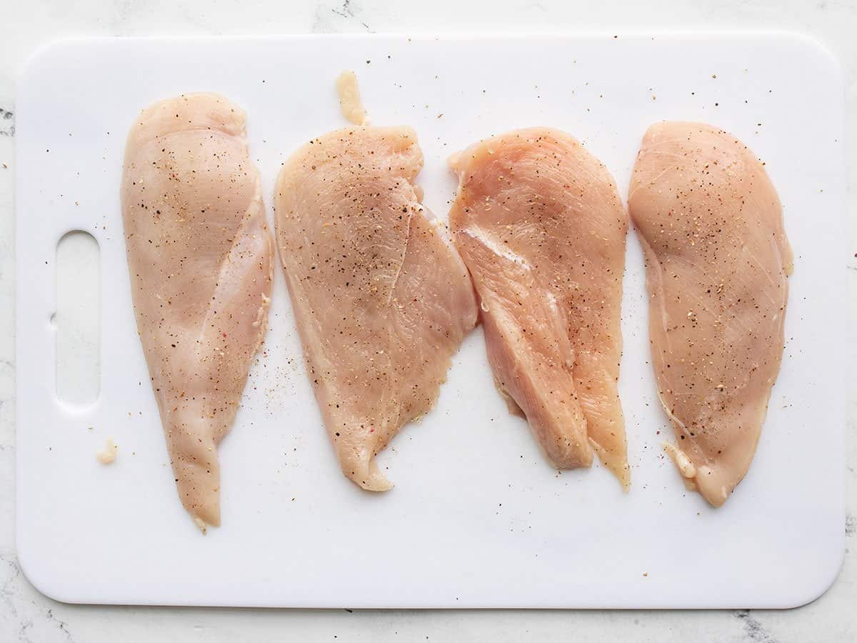filleted chicken breasts on a cutting board.