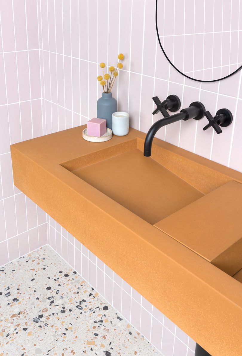 mustard yellow double bathroom sink with black wall fixtures