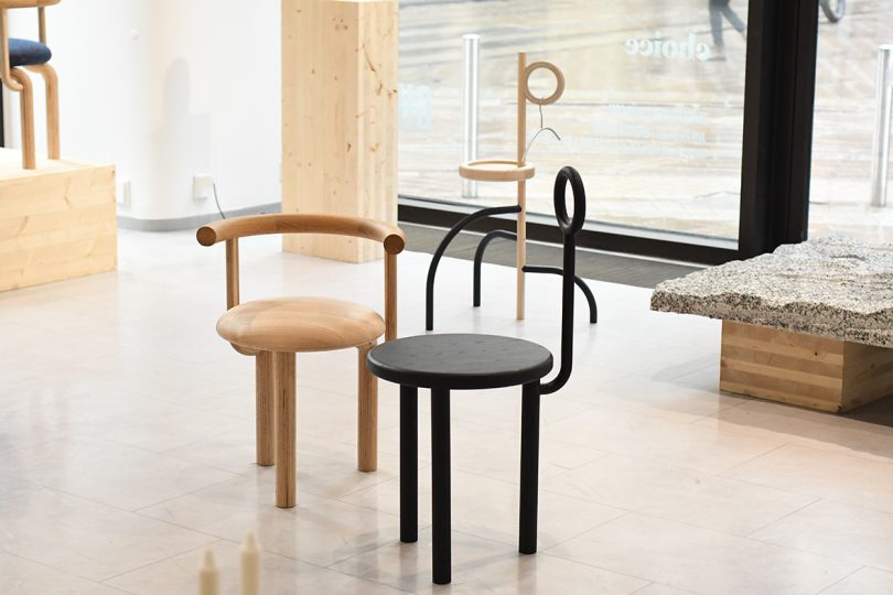 two chairs and a side table in a gallery space