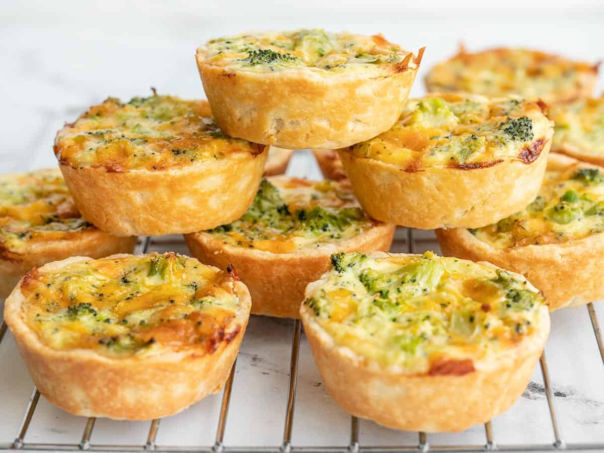 broccoli cheddar quiches on a wire cooling rack, some stacked