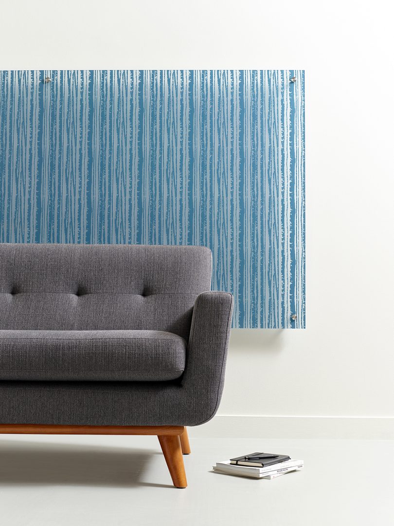 half of a modern grey couch with blue striped panel hanging behind it