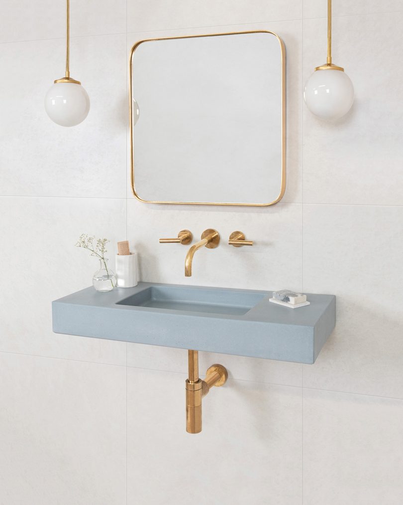 light blue grey rectangular wall sink with brass fixtures