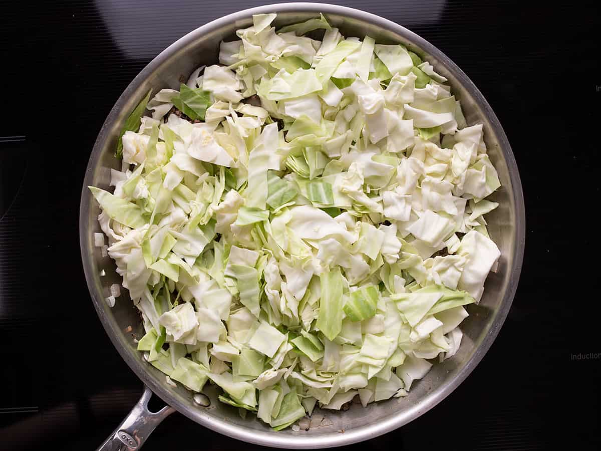 Cabbage added to the skillet.