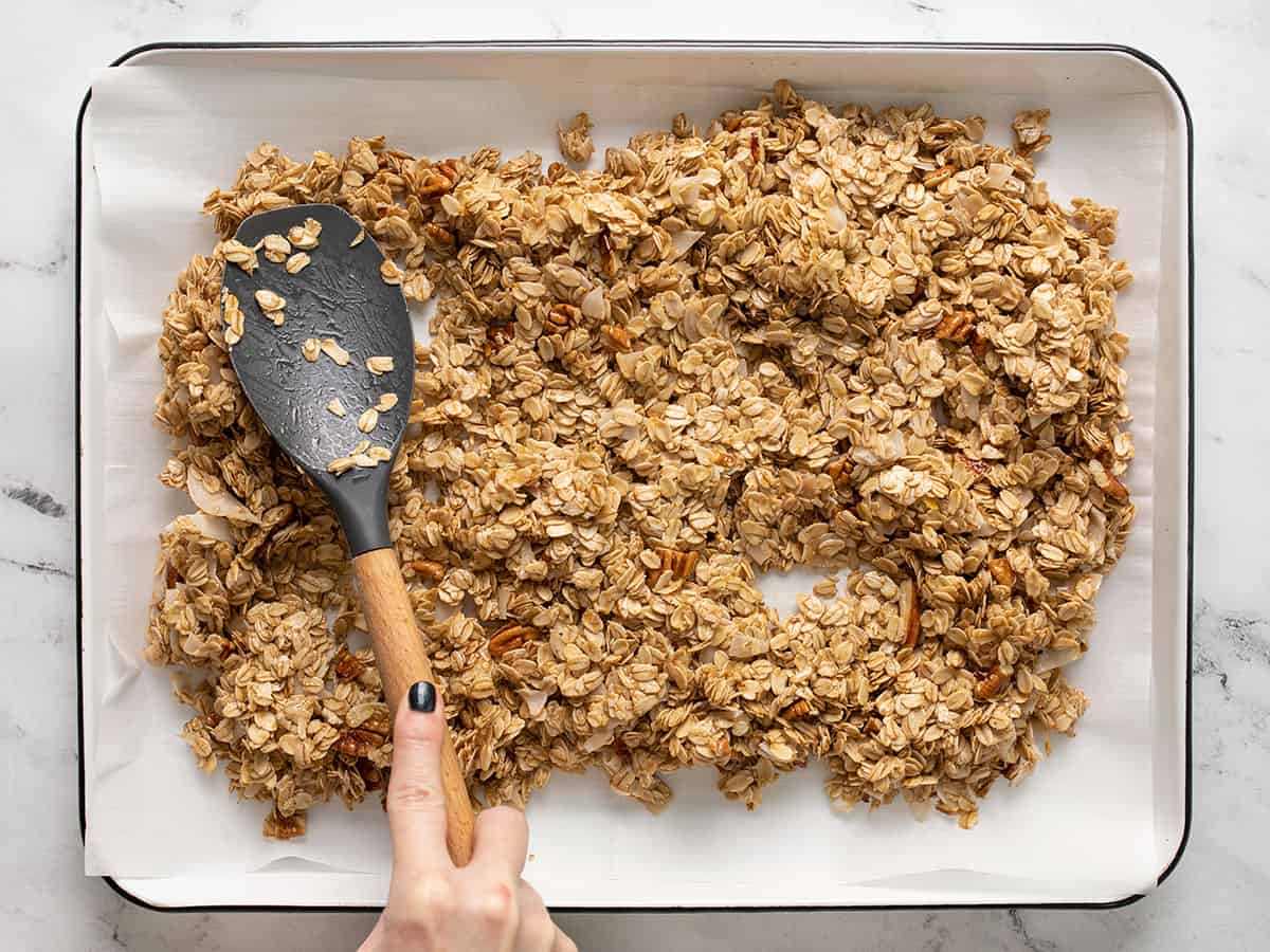 Uncooked granola being spread out onto a baking sheet.
