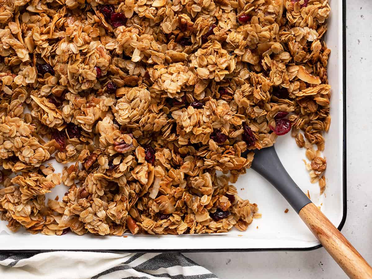 Close up of homemade granola on a baking sheet with a spatula.