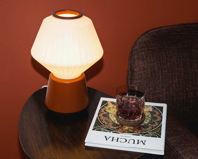 rust and white table lamp on side table with a magazine and cocktail glass