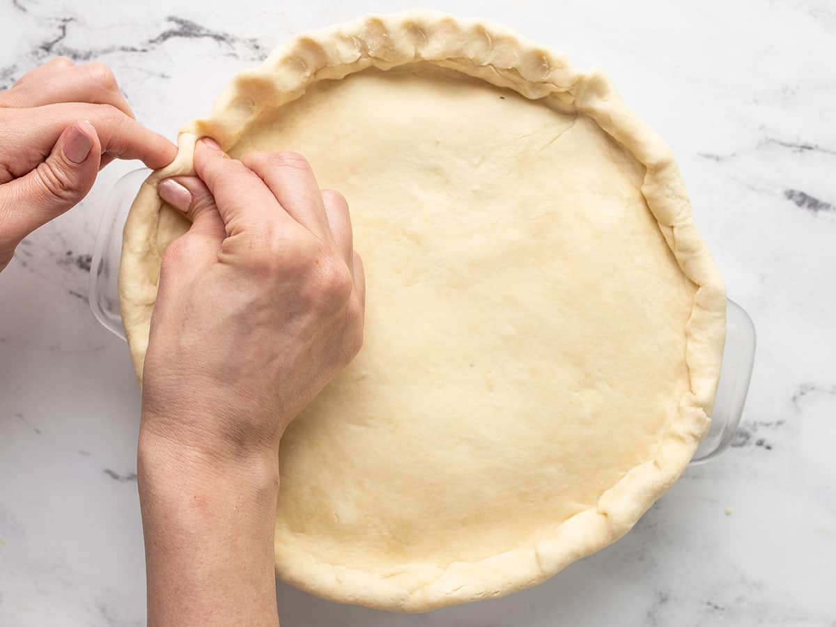Overhead shot of hands fluting pie dough.